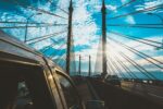 photography of vehicle traveling near suspension bridge during daytime