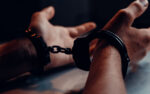 A person s hands on the table wearing handcuffs