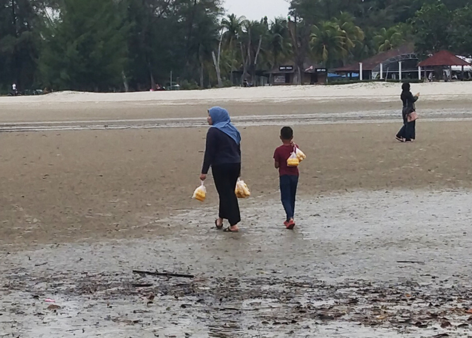 Tengku Nor Atikah Tengku Nazri berjalan mengelilingi pesisiran pantai dengan bungkusan jualan jagung rebus di Pantai Balok, Kuantan Pahang pada 10 September 2022. Foto : EDISI 9 / MOHD NAIM AZIZ