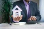 the concept of finance concept , man holding house in hand .