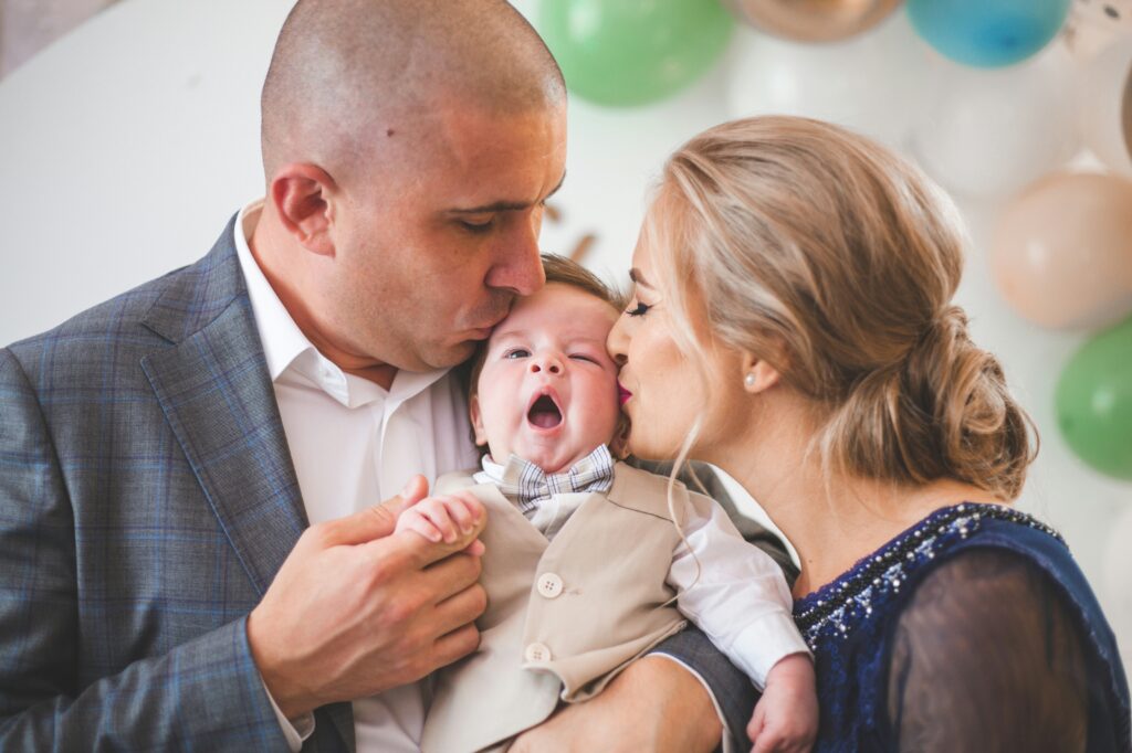 Father and mother holding and kissing son.