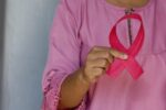 Woman holding a pink ribbon as an awareness of Breast Cancer Day, October, 1, 2020.